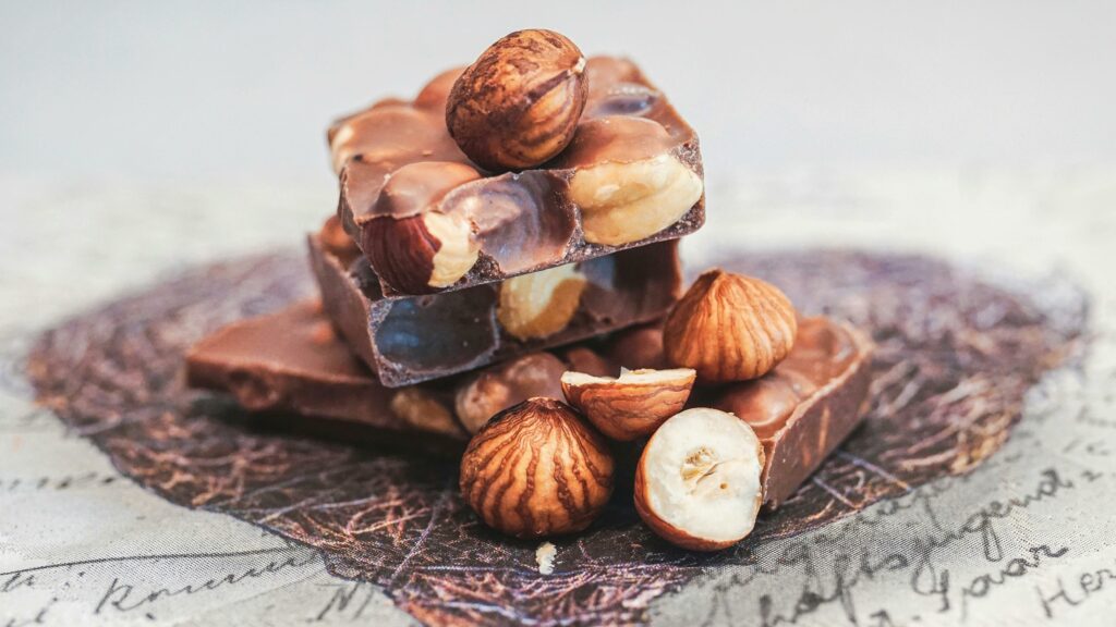 Close-up of stacked chocolate bars with whole hazelnuts, perfect for sweet indulgence.